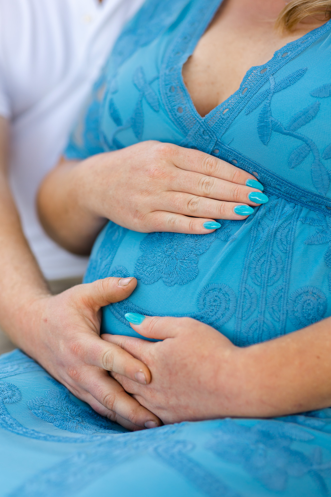 Details of a mother to be in a blue dress holding her bump doulas in savannah ga