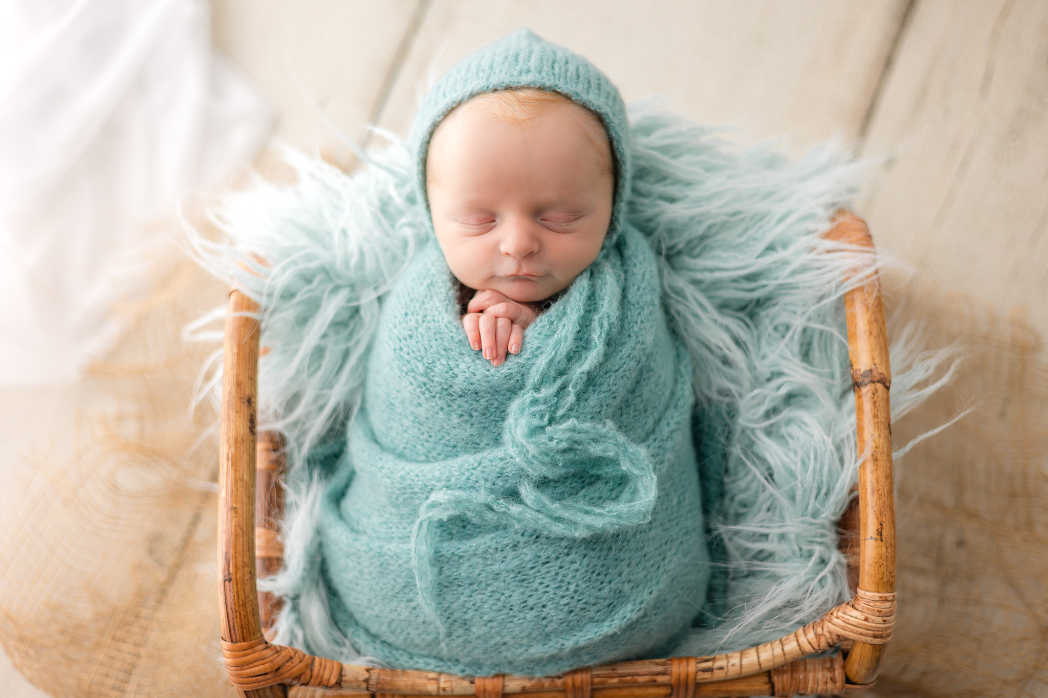 A newborn baby smiles in its sleep as it lays in a wicker basket filled with blankets