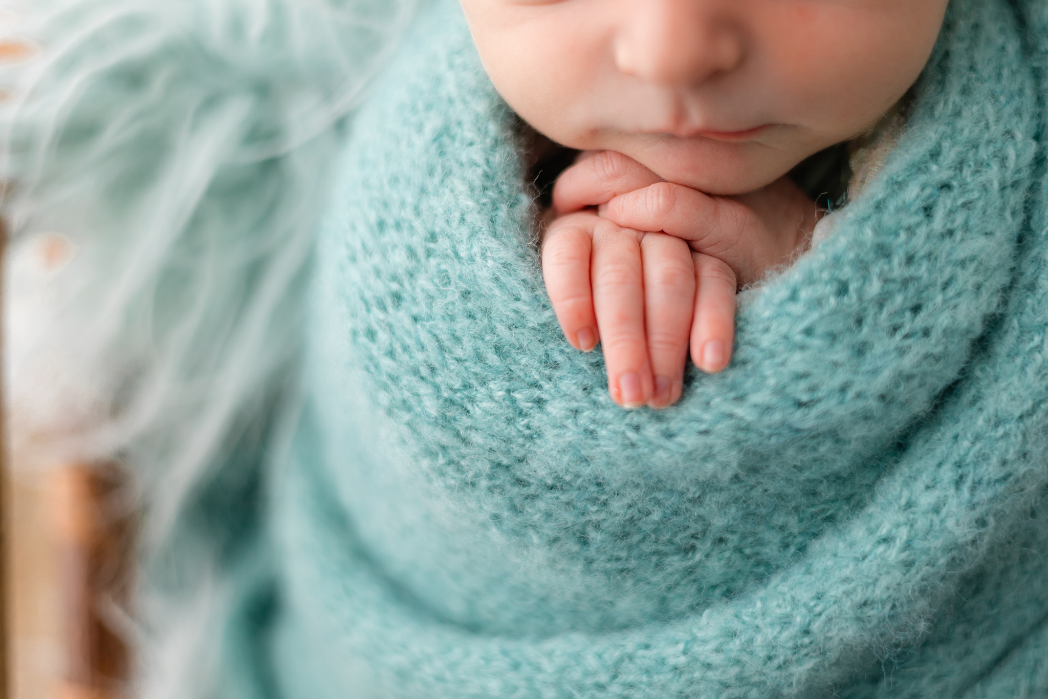 A newborn baby sleeps in a blue knit blanket with fingers sticking out childbirth classes savannah ga