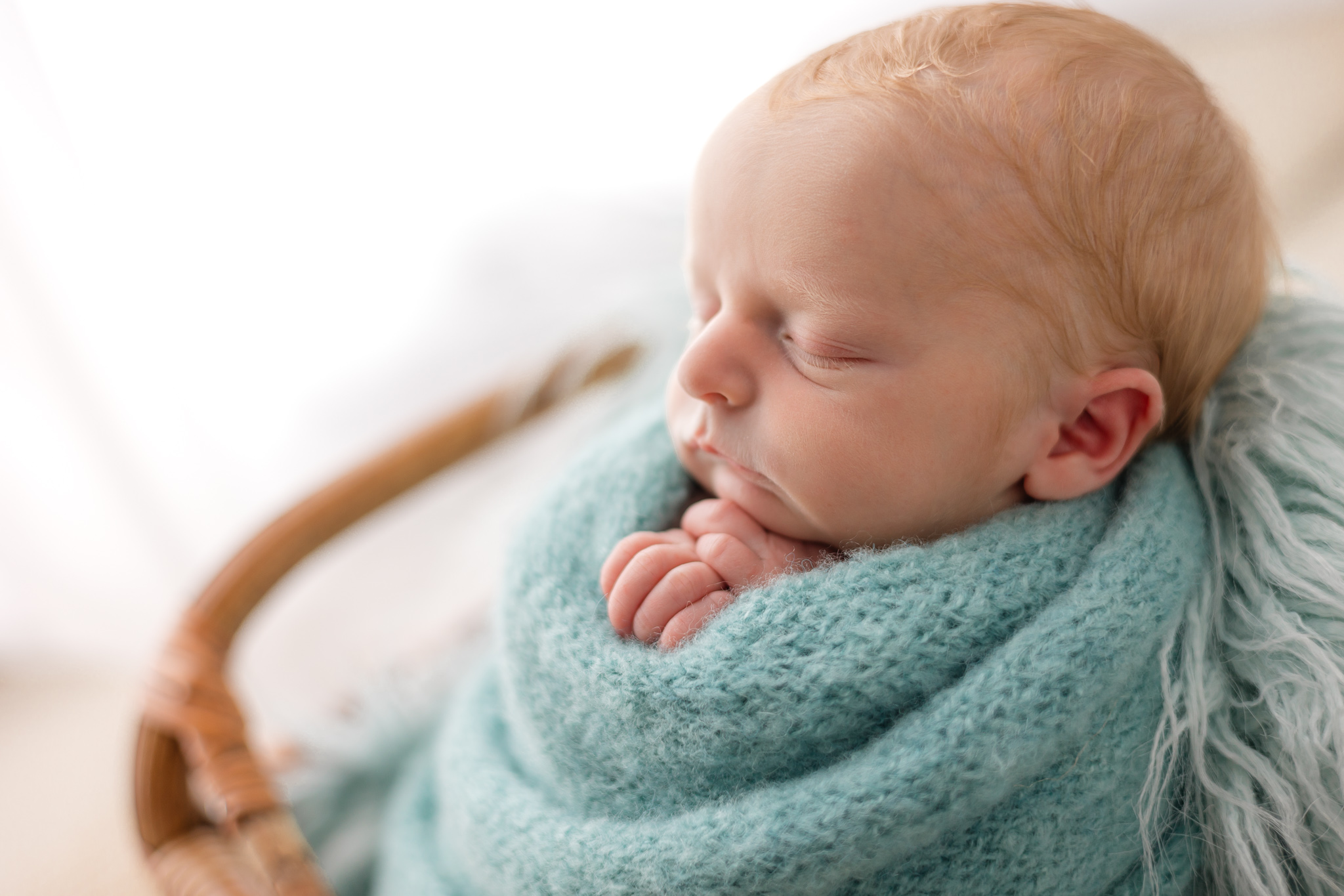 A newborn baby sleeps in a wicker basket in a blue knit blanket childbirth classes savannah ga