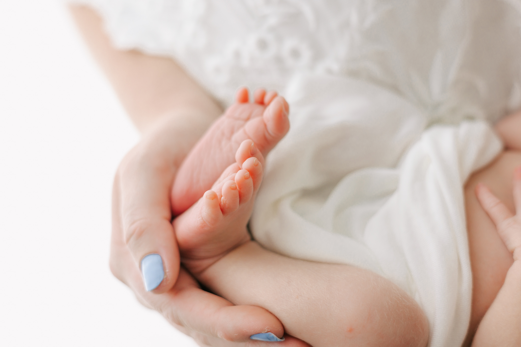 Details of a baby's feet being held by mom's hand in a white blanket Wonderfully Made 4D Ultrasound