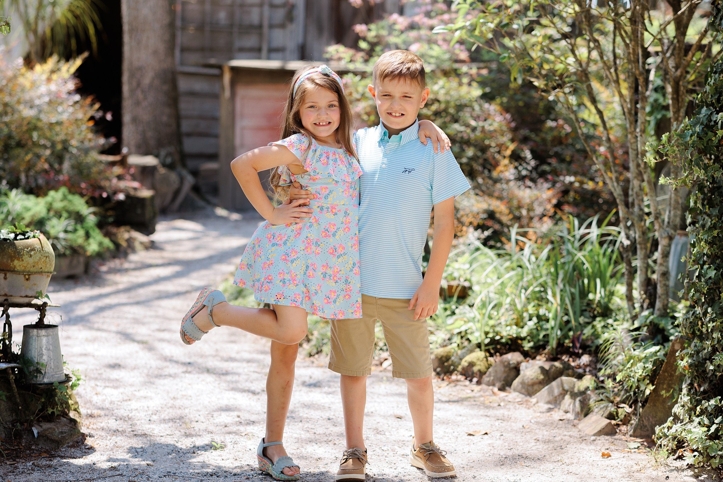 A young brother and sister stand in a garden path with arms around each other savannah pediatricians