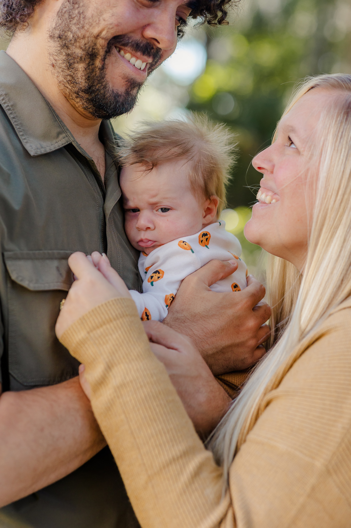 A mom and dad smile at each other while holding their infant son against dad's chest after viewing daycare pooler ga