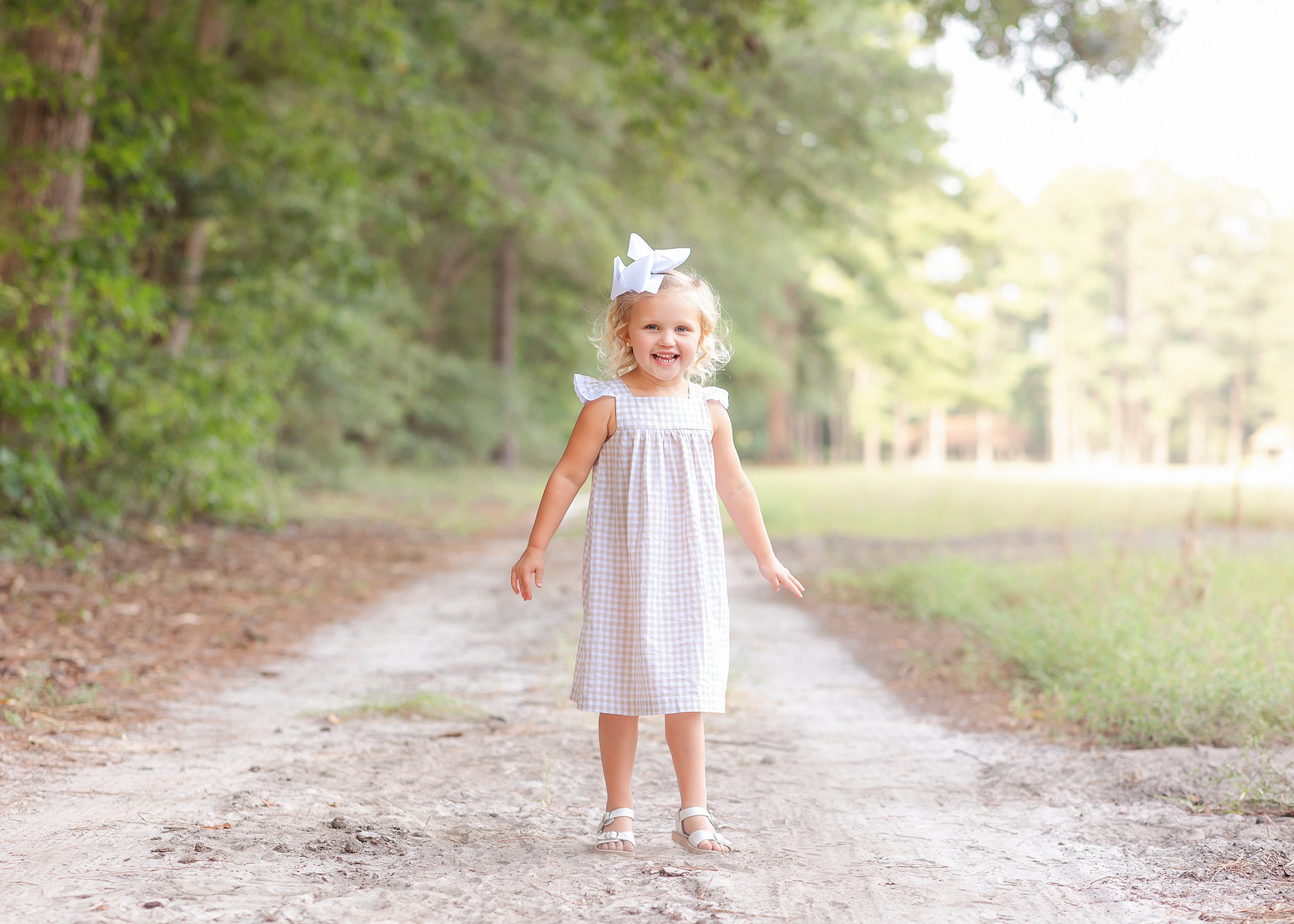 A young girl in a pink dress lays in a park trail after meeting Babysitters in Savannah, GA