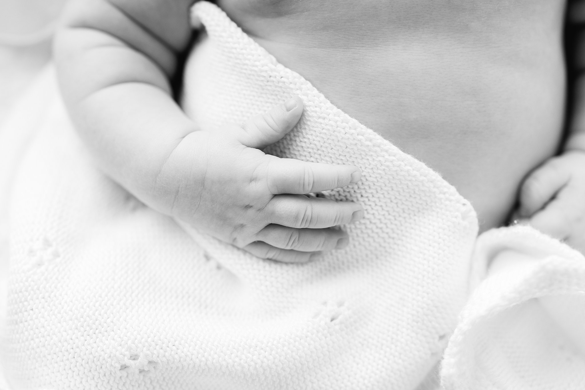 Details of a newborn baby's hand on a blanket in black and white after meeting Coastal Midwifery