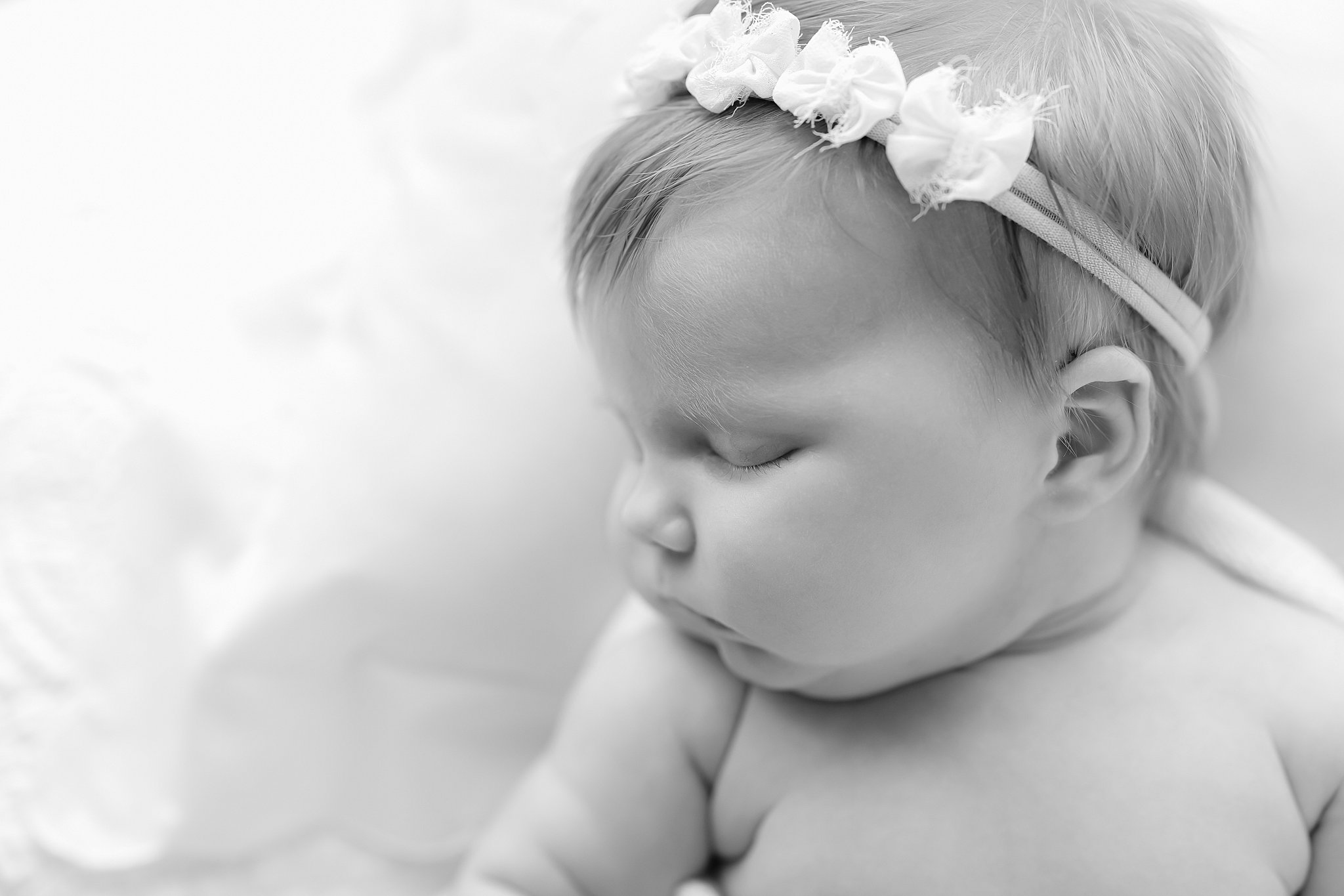 Details of a newborn baby sleeping in a bow headband thanks to Coastal Midwifery