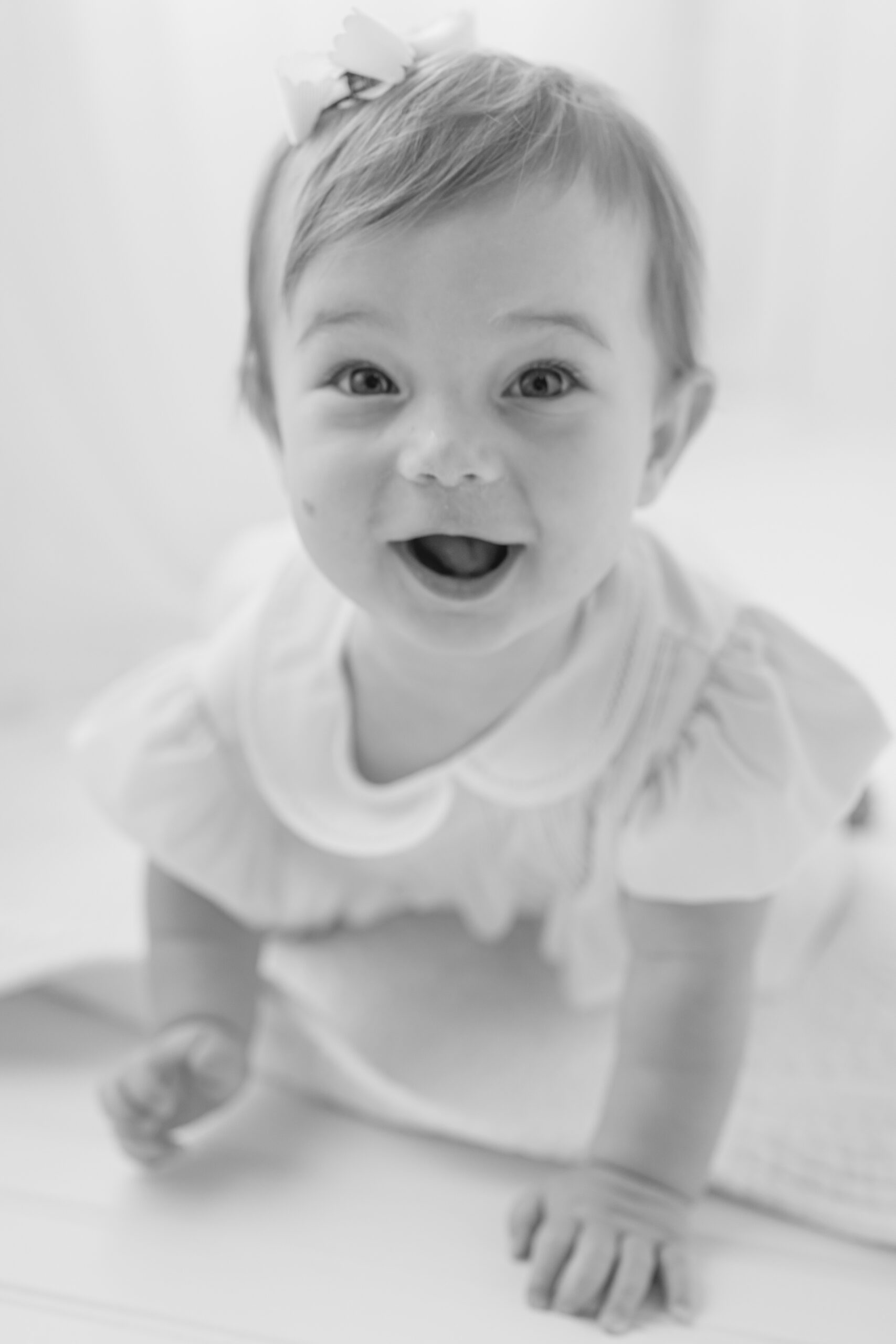 A happy baby girl crawls in a studio with a happy face