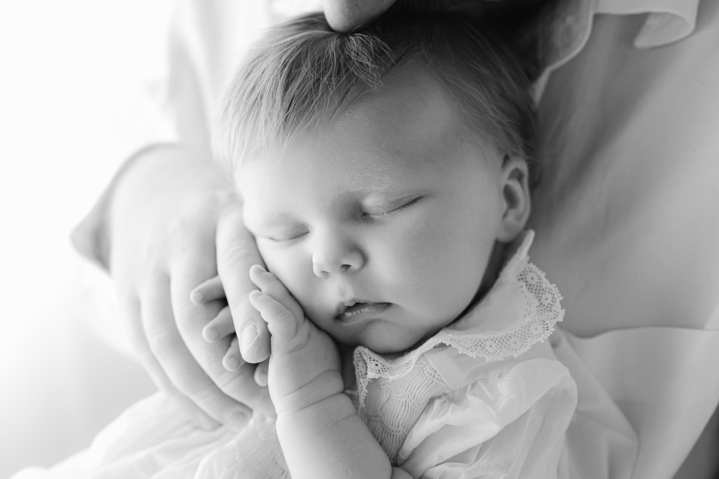 A baby sleeps in dad's lap while holding his finger before visiting family friendly restaurants in Savannah