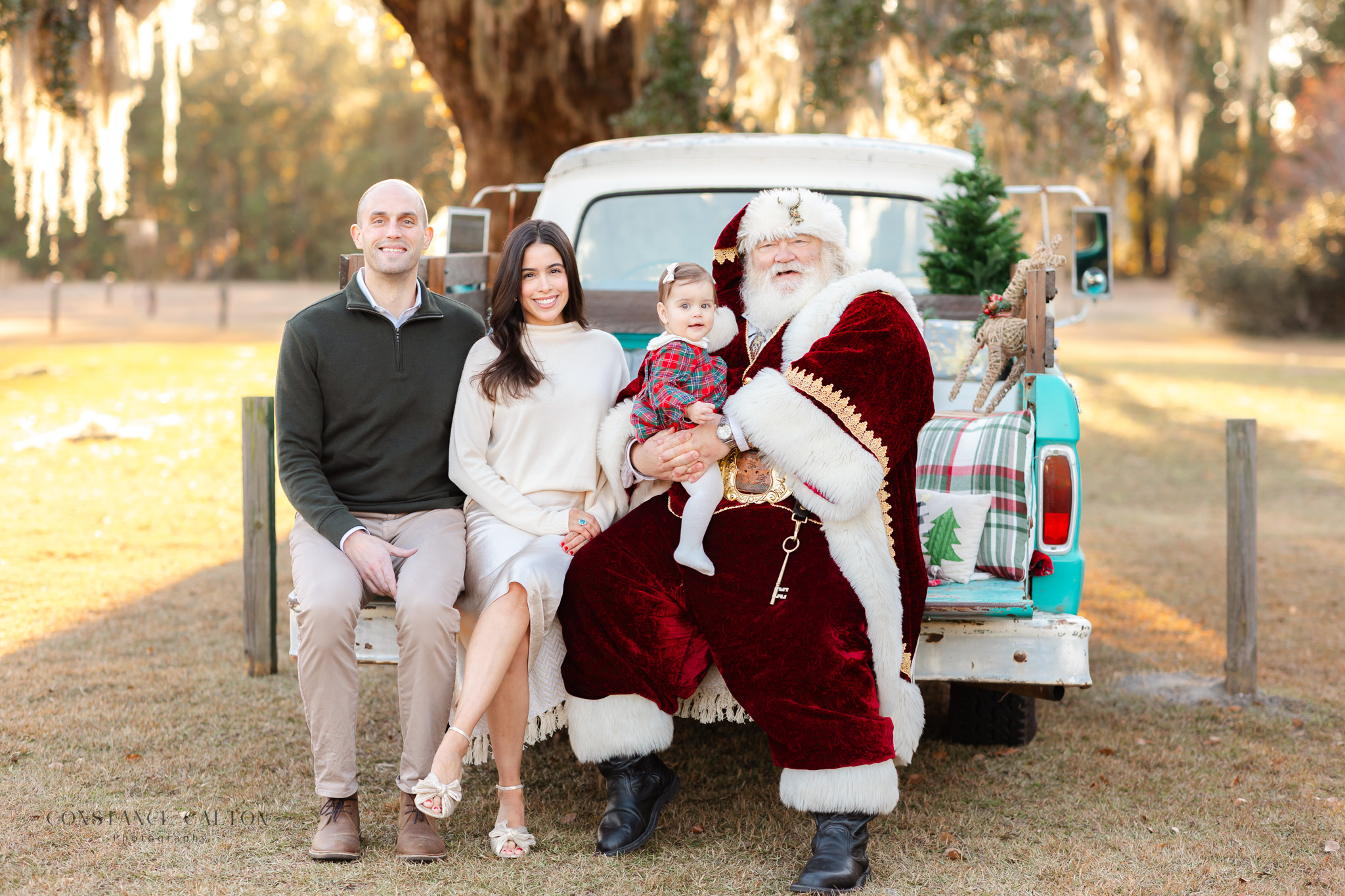 Family of 3 smiling while sitting one a classic blue truck with Santa The Best Savannah, GA Santa Sessions for Families 