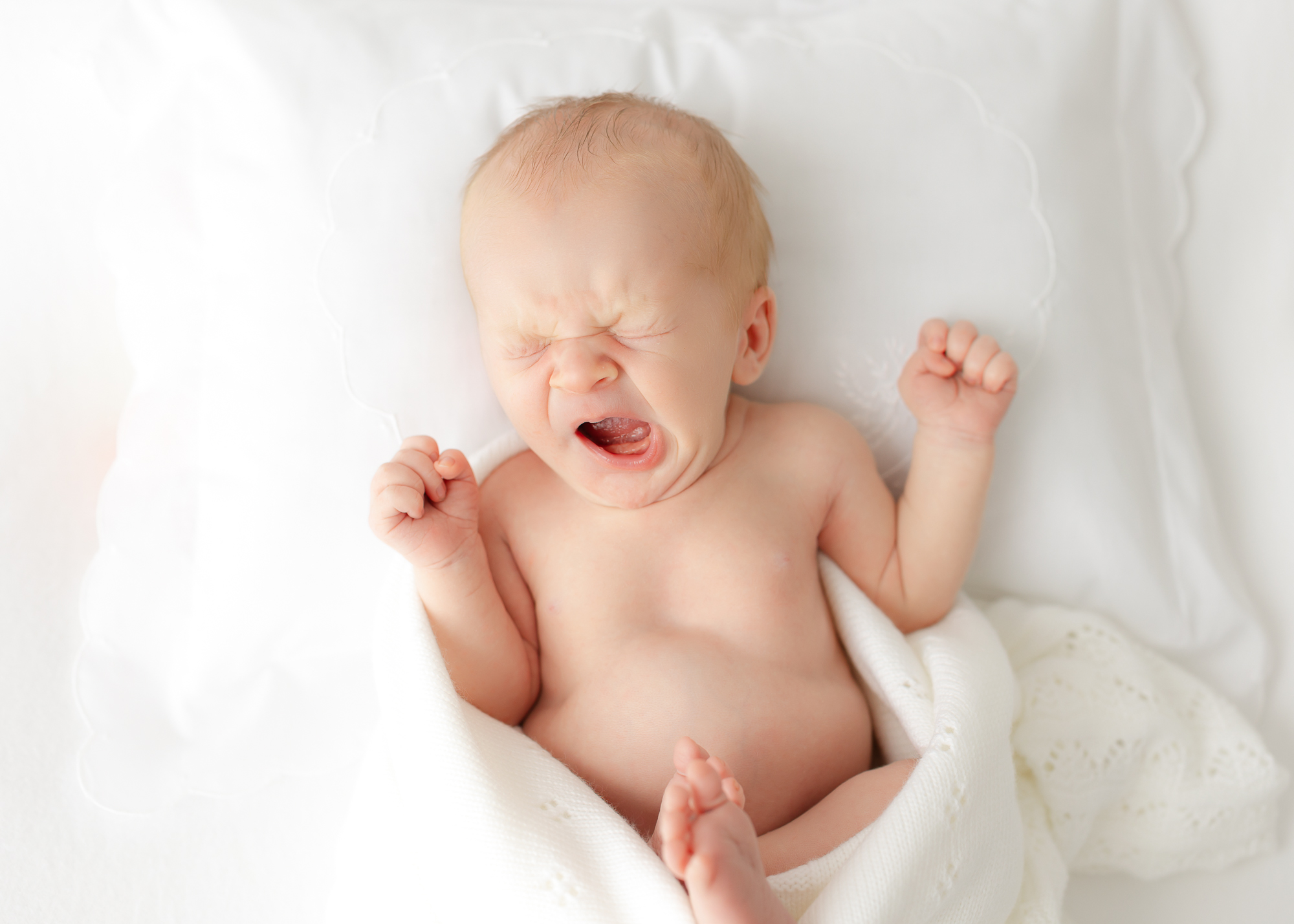 Newborn baby swaddled in soft wrap during professional photoshoot in Savannah, GA.