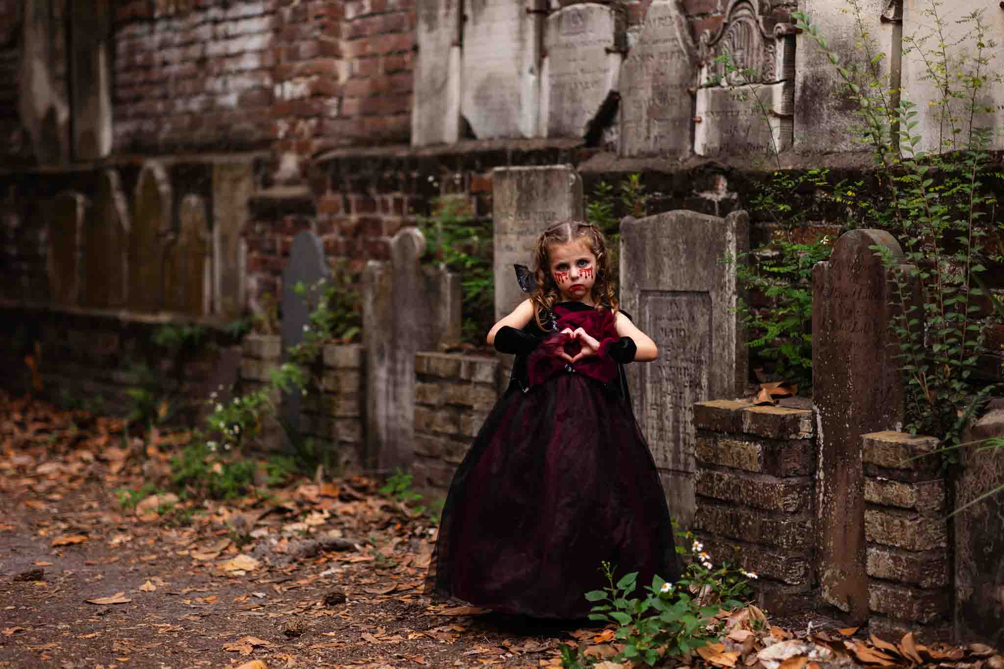 Little girl wearing a vampire costume posing in the colonial cemetery in Savannah, ga by old headstones