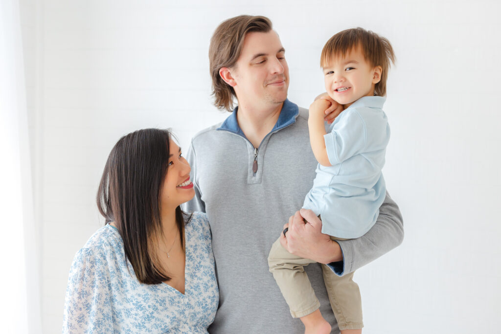 Newborn family photo outfit idea with Dad in soft blue, Mom in a blue floral dress and toddler in coordinating blue.