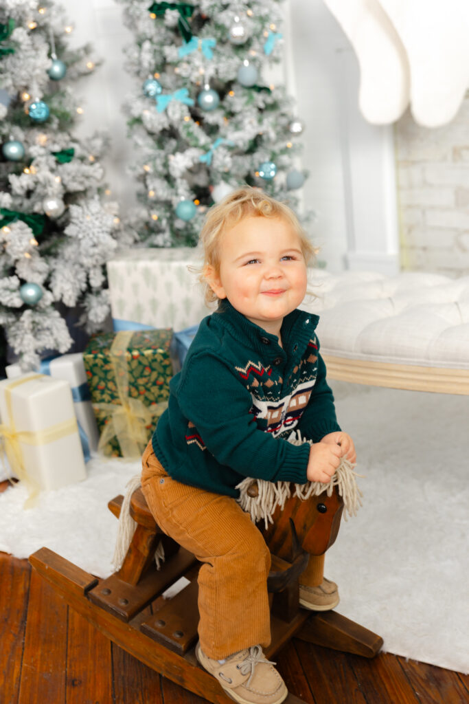 Little boy on a vintage rocking horse during Christmas photos