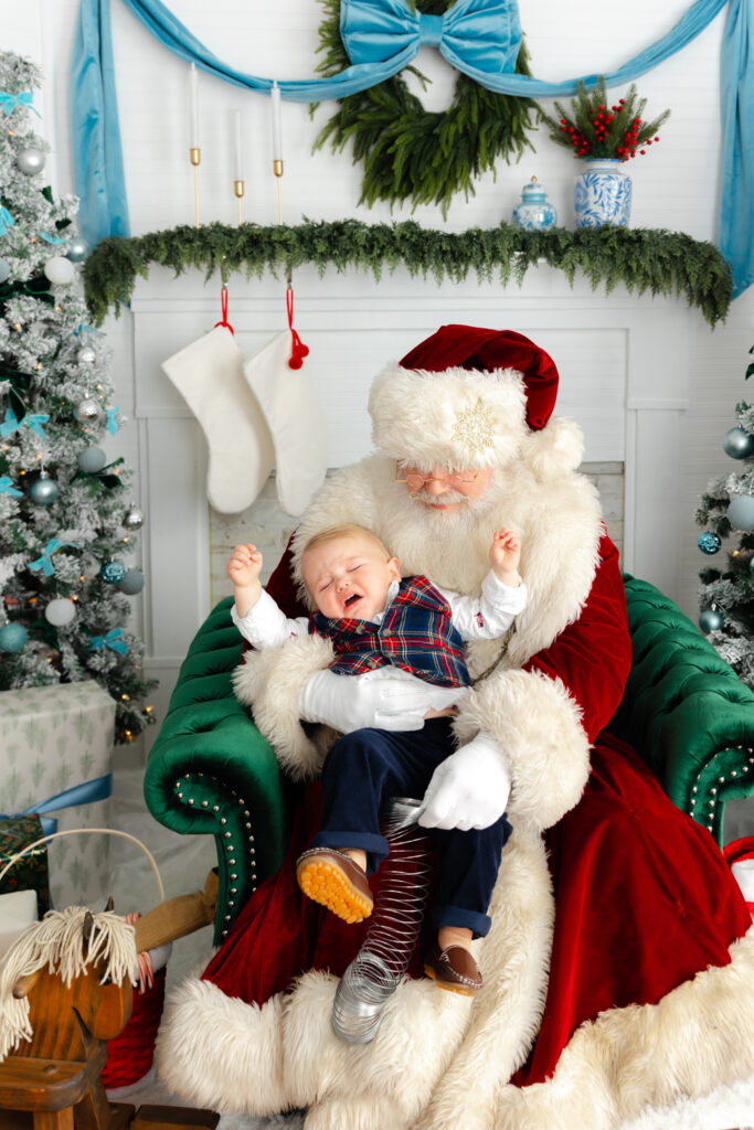 Toddler crying while sitting with Santa during a Savannah Santa photoshoot.