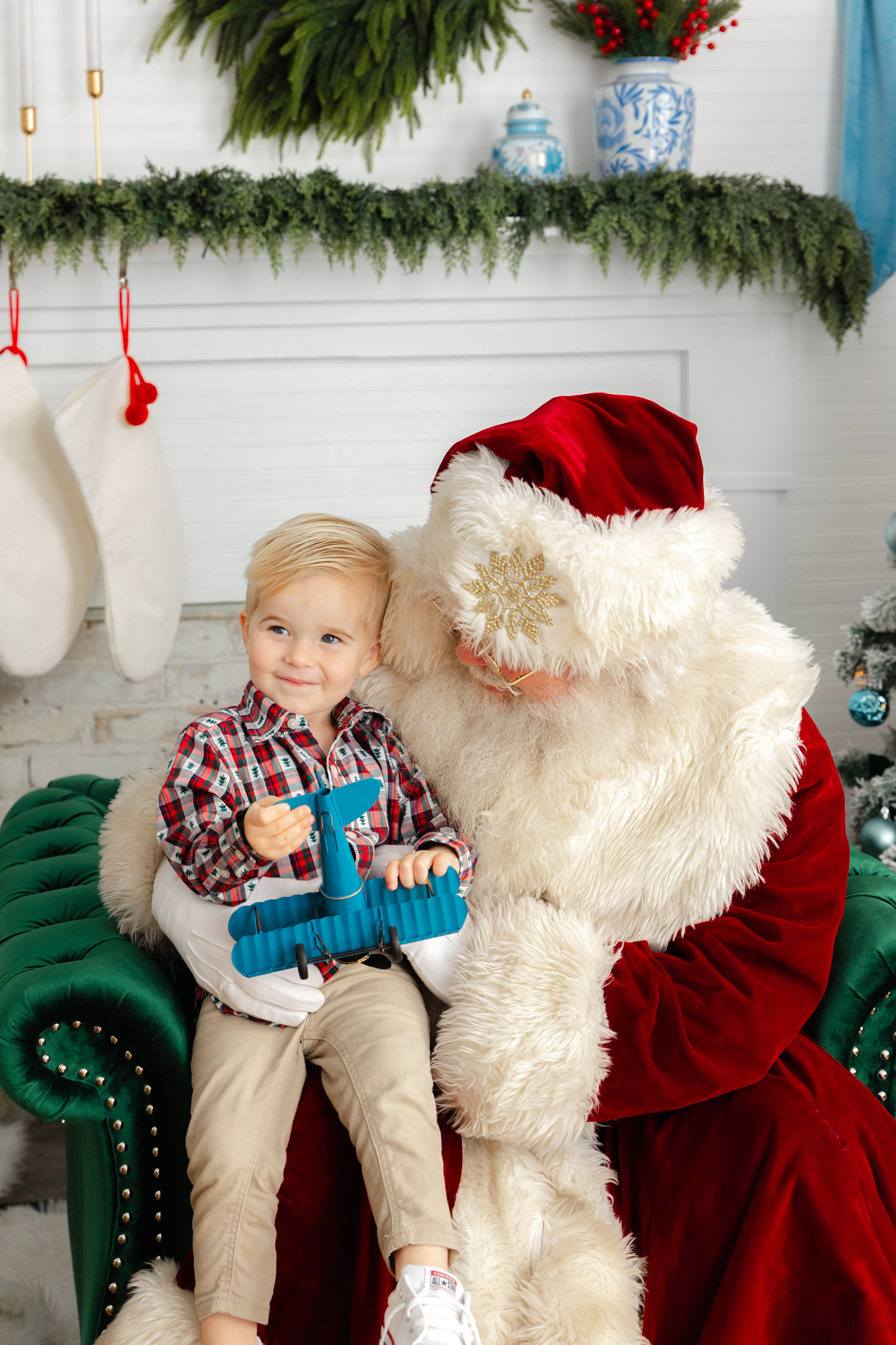 Little boy holding blue plan sitting on santa's lap