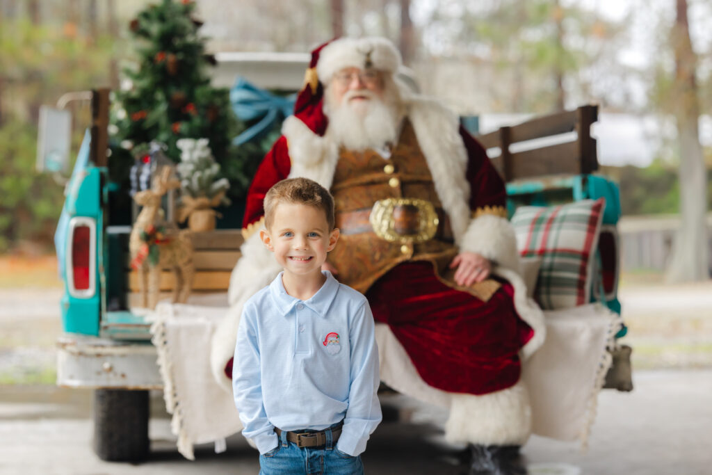 Smiling boy posing in front of Santa during a Savannah Santa Experience.