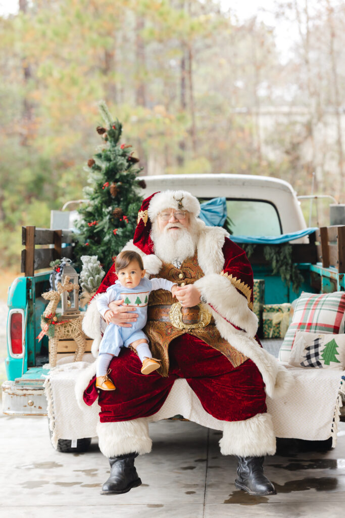Santa Experience Savannah, GA featuring a baby on Santa's lap in a festive Christmas truck setting.