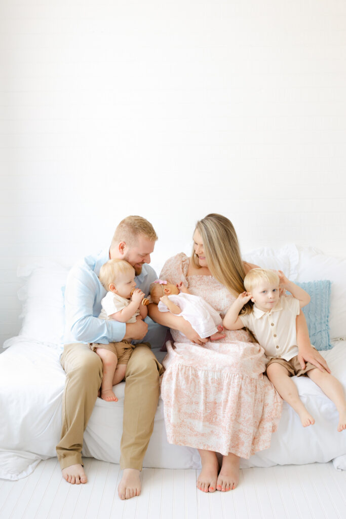 Coordinating newborn family photo outfits in soft blues, creams and neutrals for a studio newborn session.
