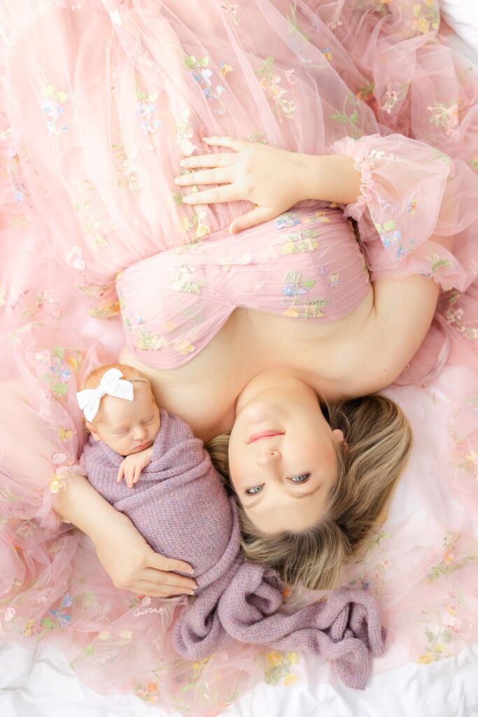 Mom wearing a feminine pink floral dress while snuggling her newborn baby during a Savannah studio newborn session.