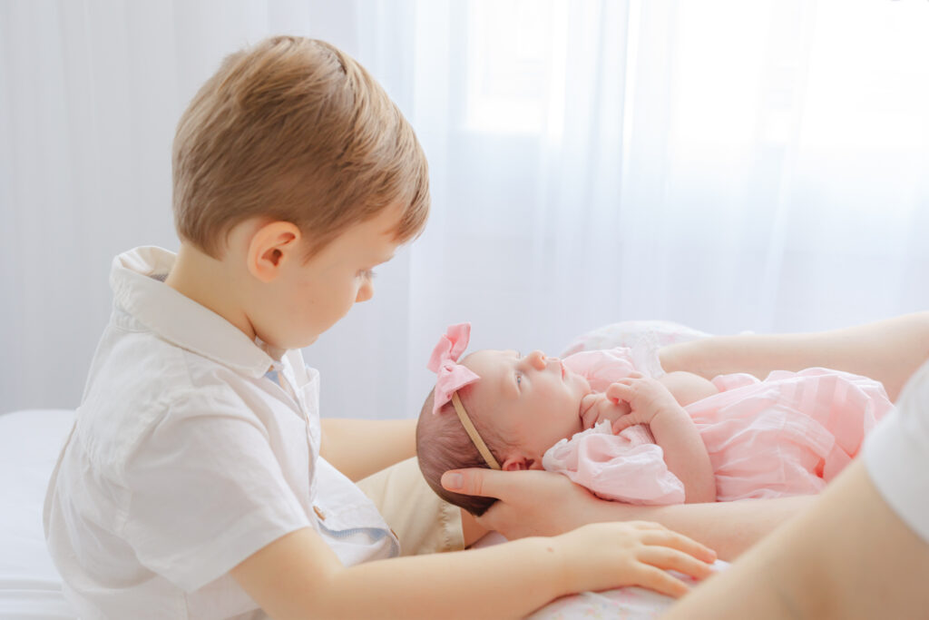 Toddler big brother gently interacting with his newborn sister during a studio newborn session in Savannah GA.