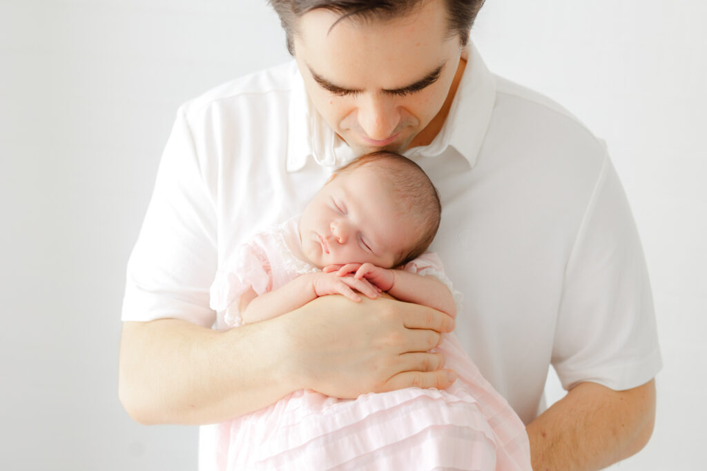 Dad holding and kissing his newborn baby girl during a Savannah newborn photography session.