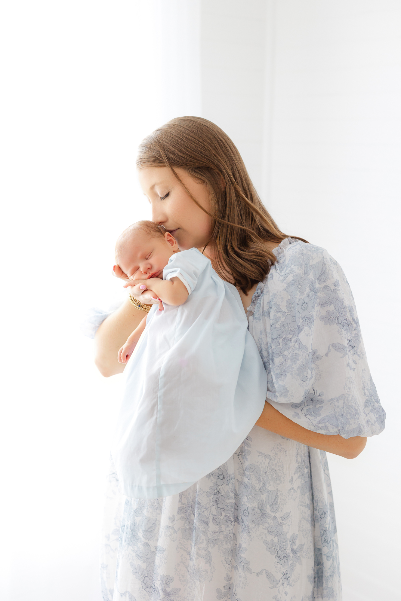 Mom wearing a soft blue floral dress while cuddling her newborn, a beautiful mom outfit for newborn photos.